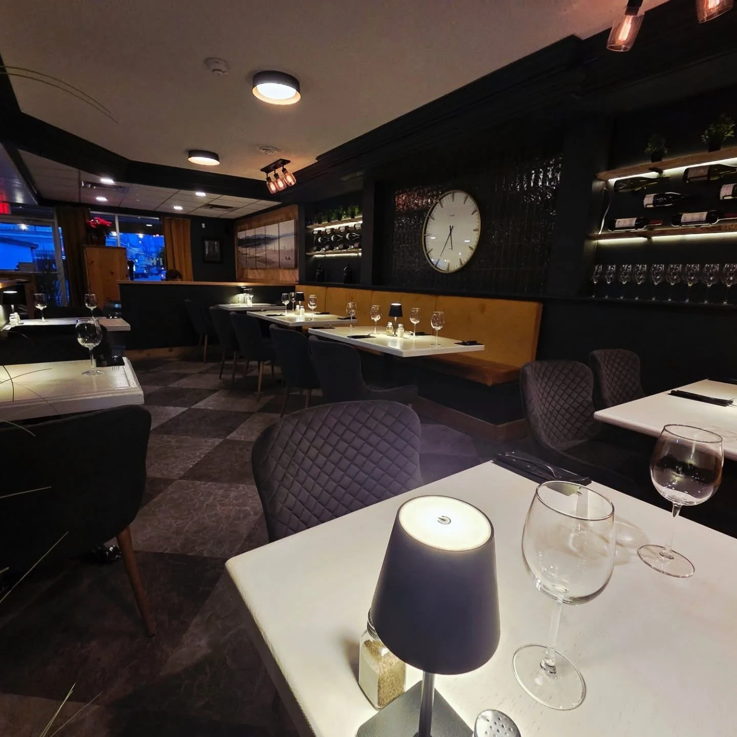 Soft table lighting, a wine display and dark chairs in Trio’s intimate dining room